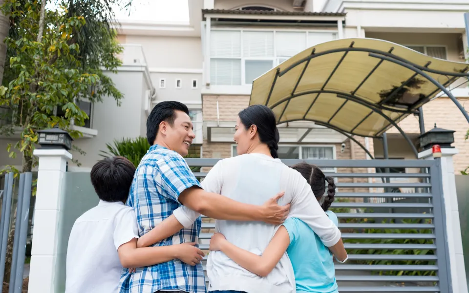 a family holding each other facing their new home - LasVegasRealEstate.com