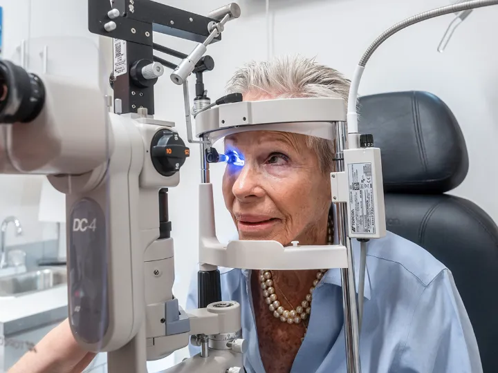 Older woman receiving eye exam with slit lamp biomicroscope