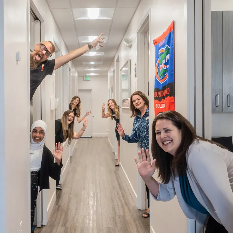 Friendly clinic staff smiling and waving in a hallway
