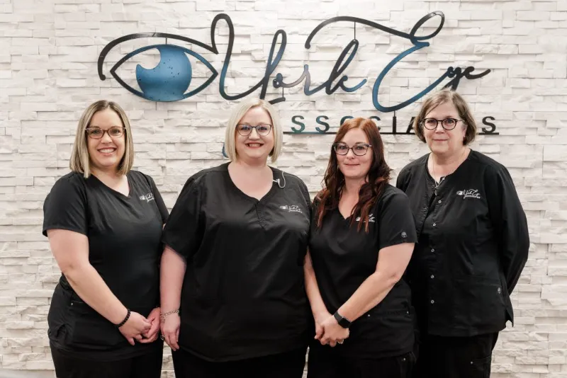York Eye Associates staff smiling in front of clinic logo