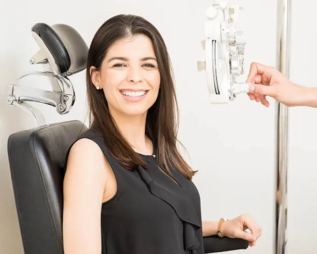Smiling woman sitting in exam chair during eye test at clinic