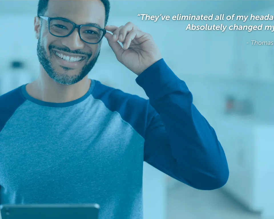 Smiling man adjusting glasses while using digital tablet indoors